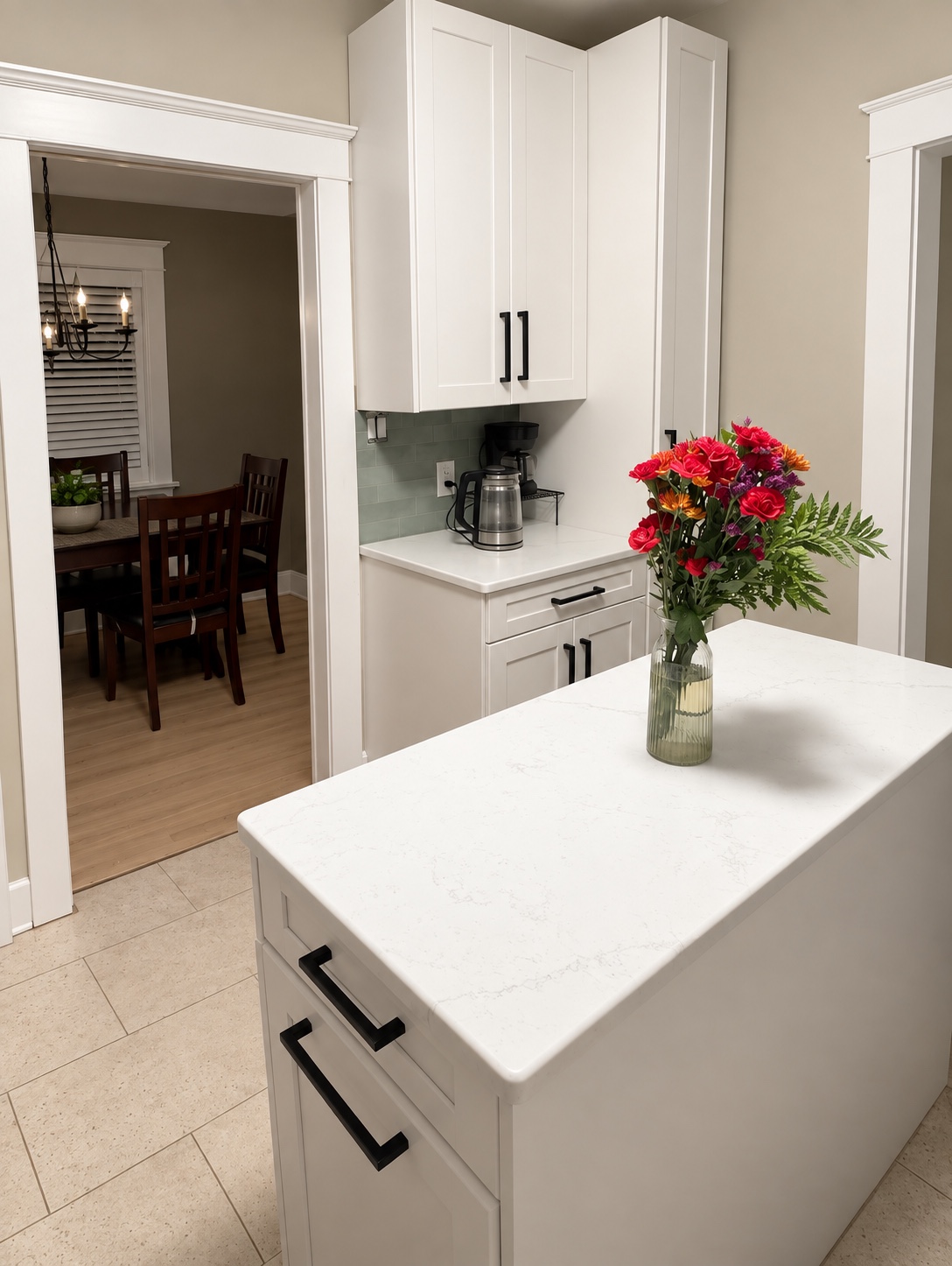 Completed kitchen island and coffee station with bright white shaker cabinetry and black hardware