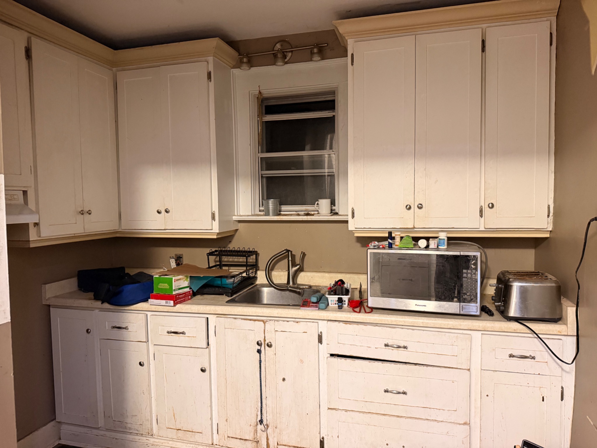 Worn older white kitchen cabinets and dated counter before renovation